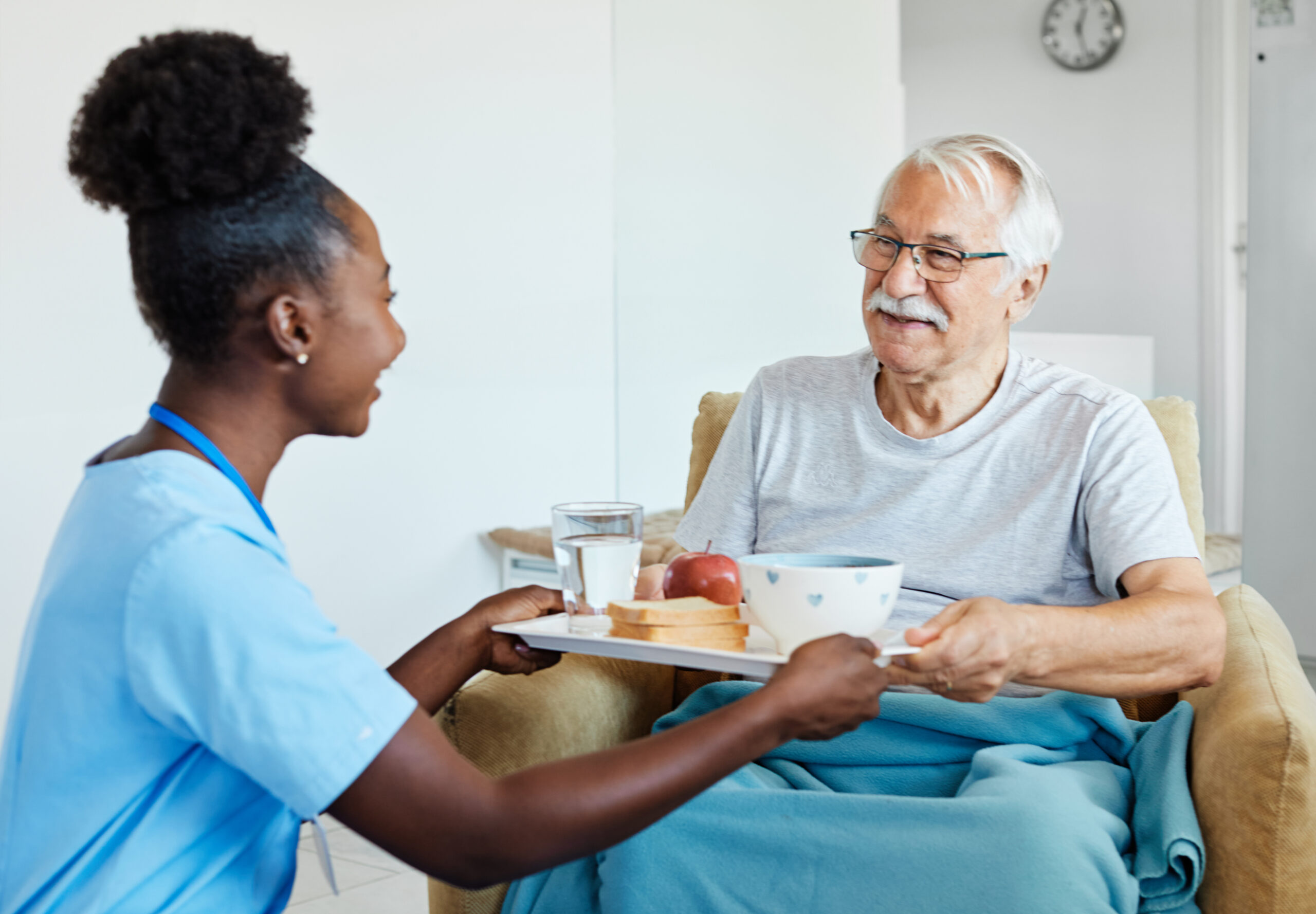 Caregiver assisting an individual with everyday mealtime routines in a home setting